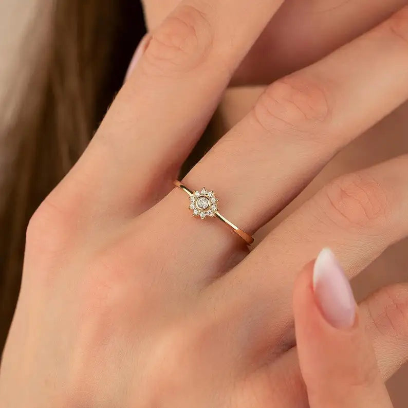 Gold diamond engagement ring with a floral design and clear gemstones.